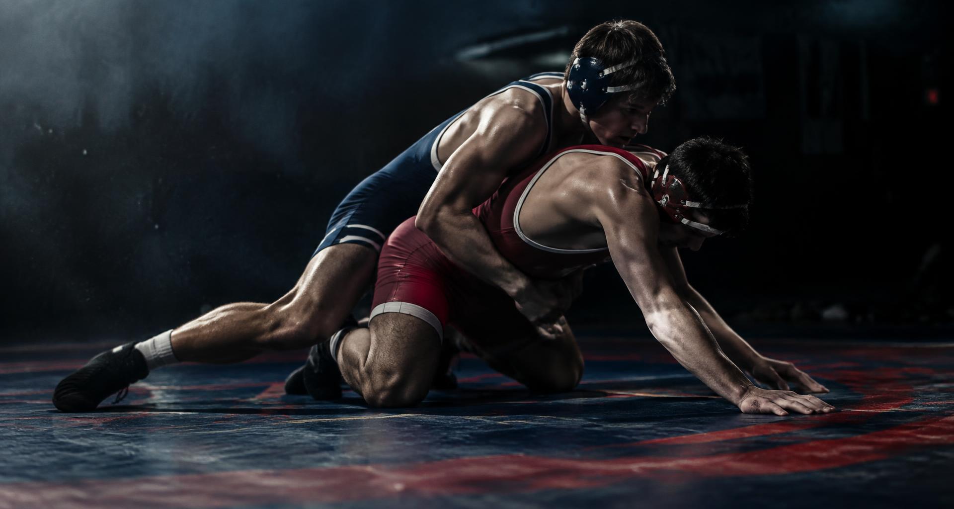 Two amateur wrestlers locked in a takedown on a mat